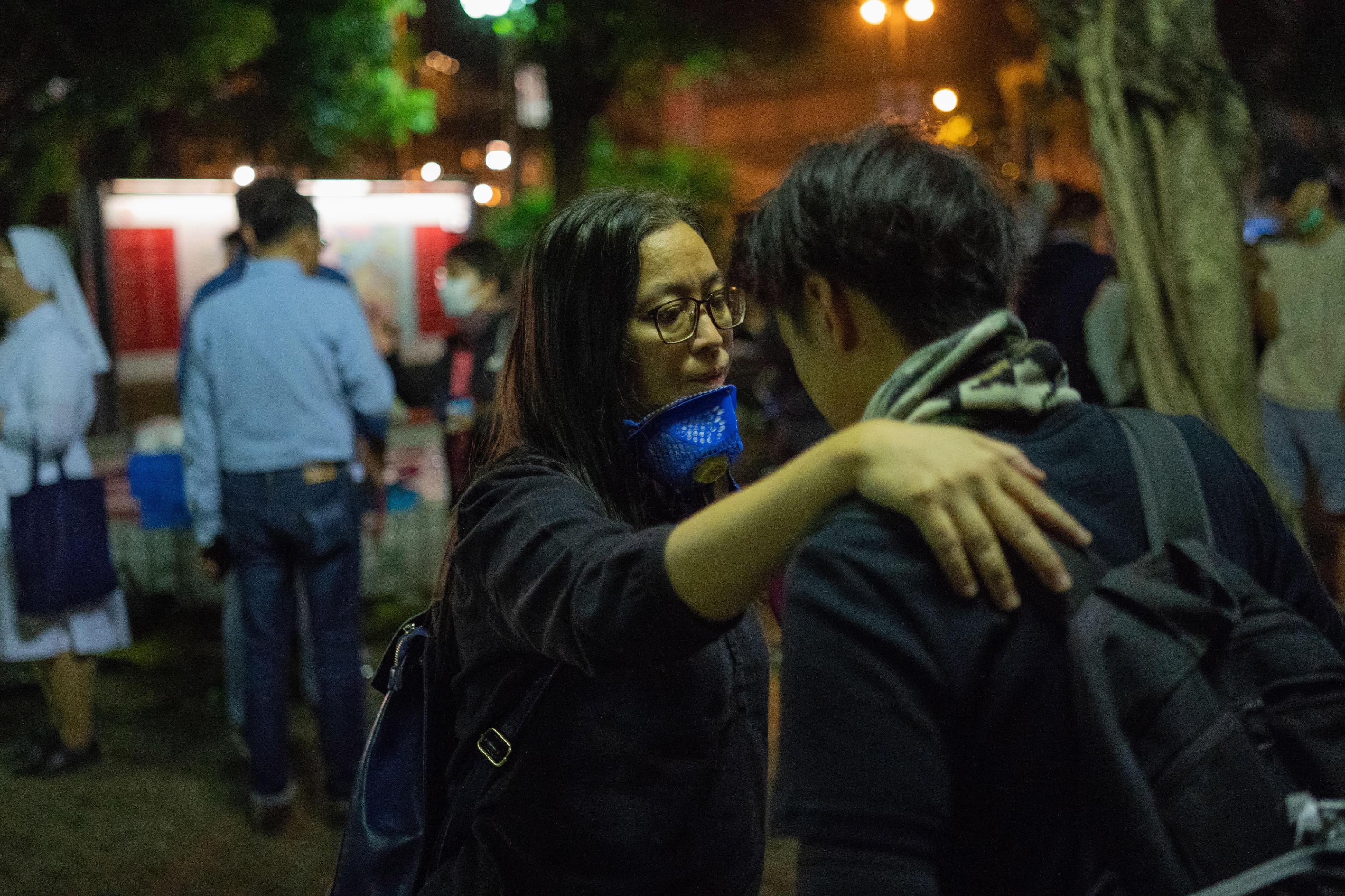 epa08007279 A teacher (C) reacts next to a student as they leave the Hong Kong Polytechnic University (PolyU) campus in Hong Kong, China 19 November 2019. Hong Kong is in its sixth month of mass protests, which were originally triggered by a now withdrawn extradition bill and have since turned into a wider pro-democracy movement.  EPA/BING GUAN