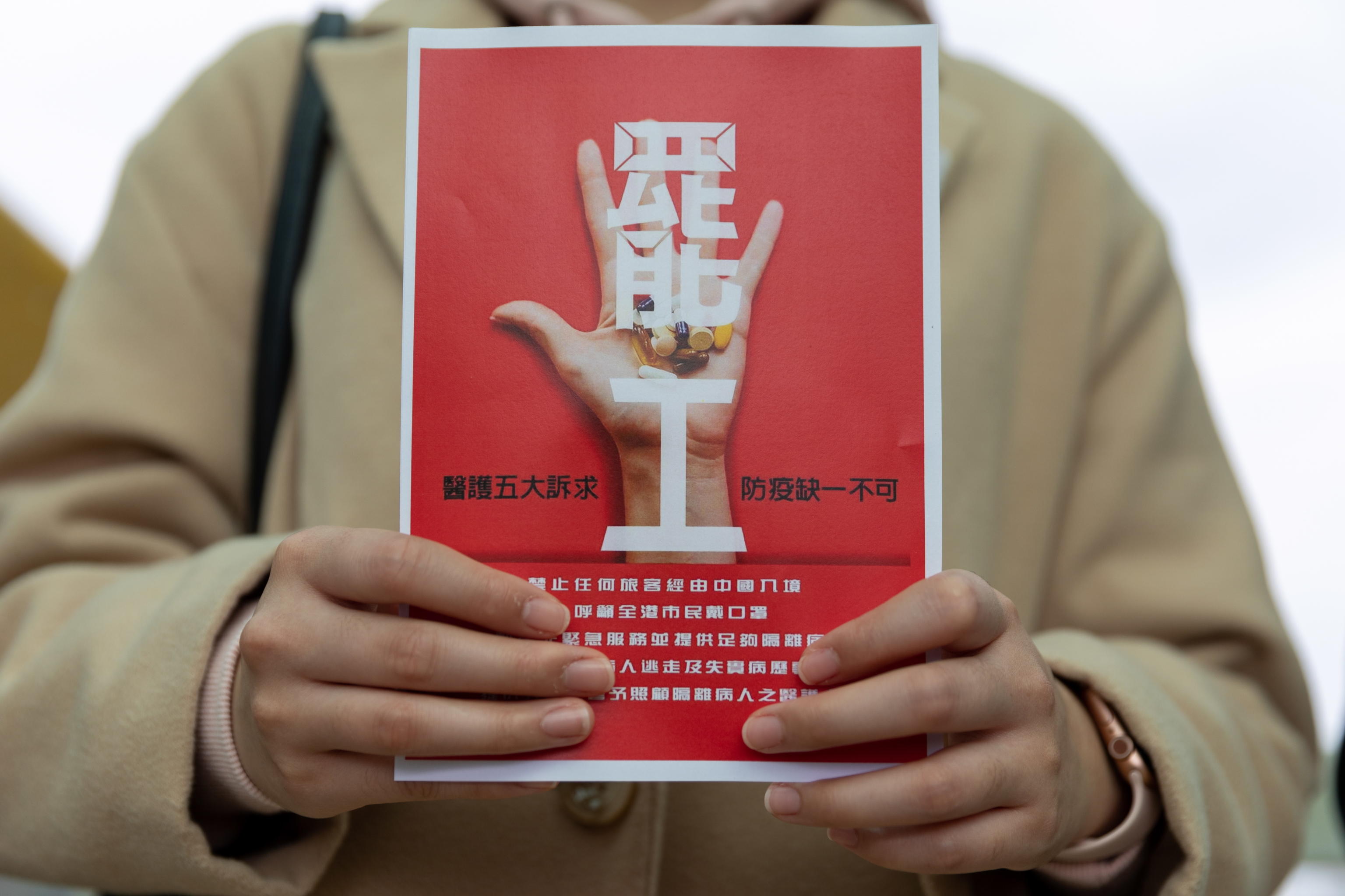epa08189571 A medical worker on strike holds a placard reading 'strike', on a footbridge near Queen Mary Hospital in Hong Kong, China, 03 February 2020. Thousands of hospital and medical workers pushed ahead with a strike starting from 03 February demanding a total closure of Hong Kongs borders with mainland China to help contain the novel coronavirus outbreak. Hong Kong confirmed its 15th case of coronavirus infection on 02 February. The outbreak originated in the Chinese city of Wuhan and has so far killed at least 361 people with over 17,000 infected, mostly in China.  EPA/JEROME FAVRE