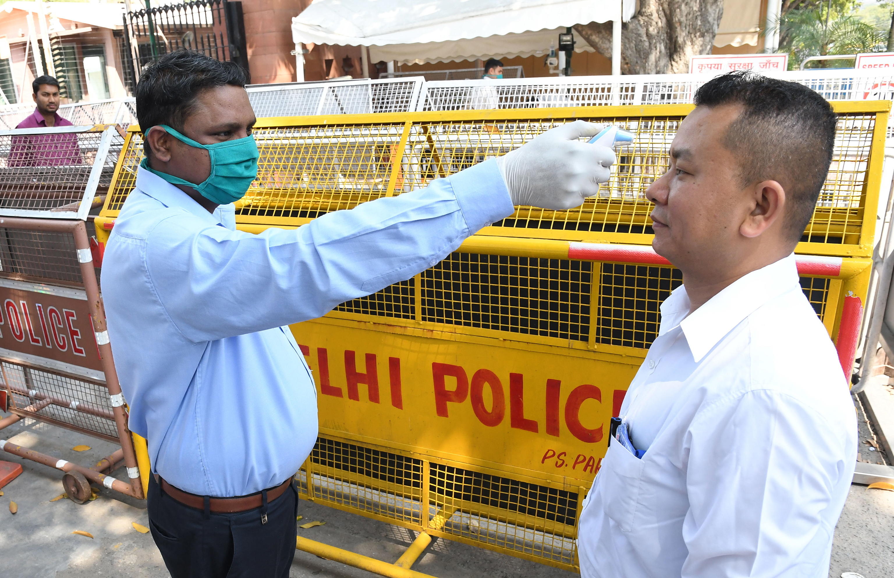 epa08305993 An official checks the temperature of a visitor at the Parliament House gate in New Delhi, India, 19 March 2020. According to news reports, all educational institutions in New Delhi have been shut down until 31 March in an effort to contain the spread of the ongoing pandemic of the COVID-19 disease, caused by the SARS-CoV-2 coronavirus. In addition, gyms, movie theaters, swimming pools and monuments across the state of New Delhi have also been ordered to close their doors. The number of confirmed cases of COVID-19 in the South Asian country has climbed up to 179.  EPA/STR