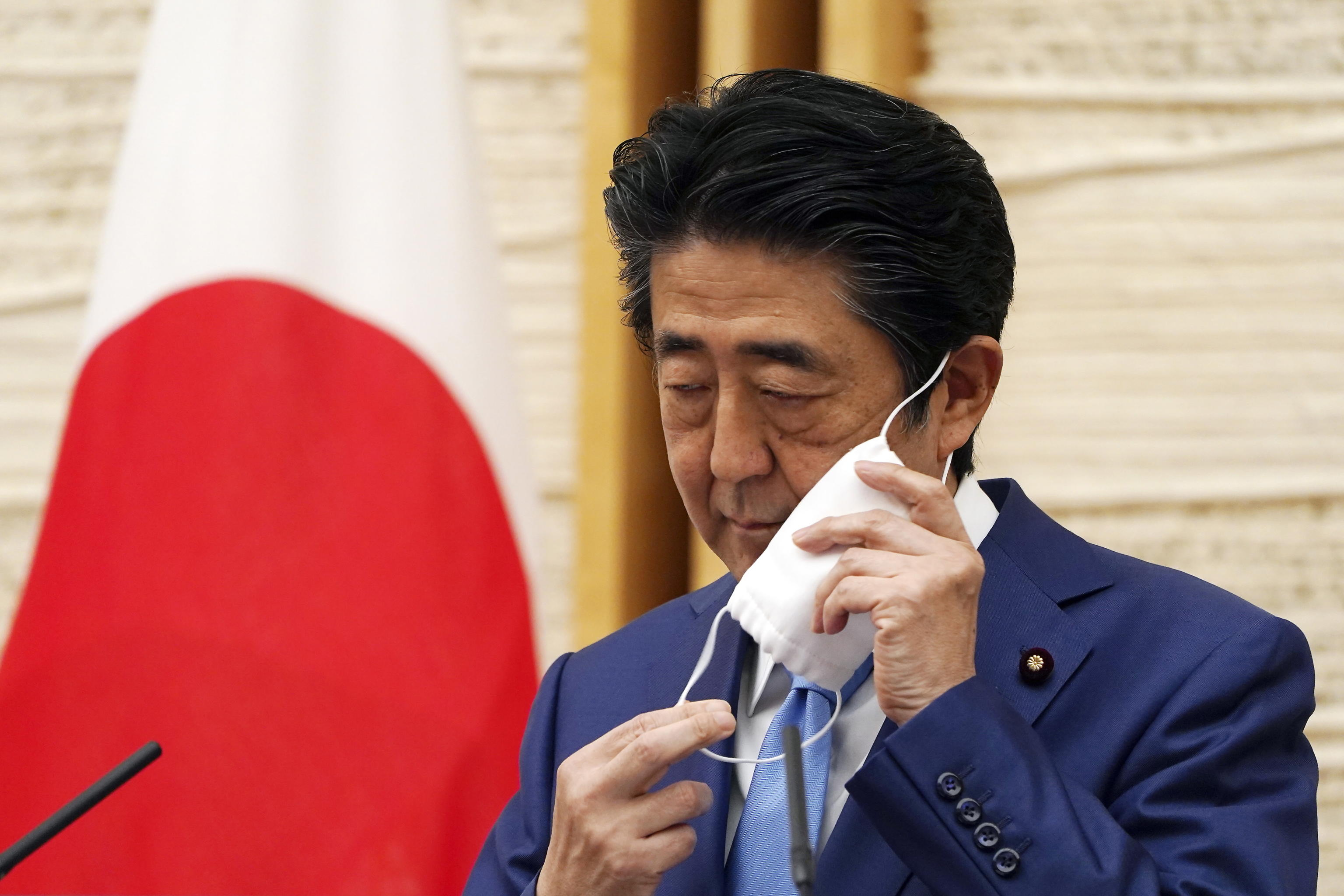 epa08399737 Japanese Prime Minister Shinzo Abe removes a face mask to help curb the spread of the coronavirus before speaking at a press conference where he announced an extension of the nation's state of emergency at the Prime Minister's Office in Tokyo, Japan, 04 May 2020.  EPA/EUGENE HOSHIKO / POOL
