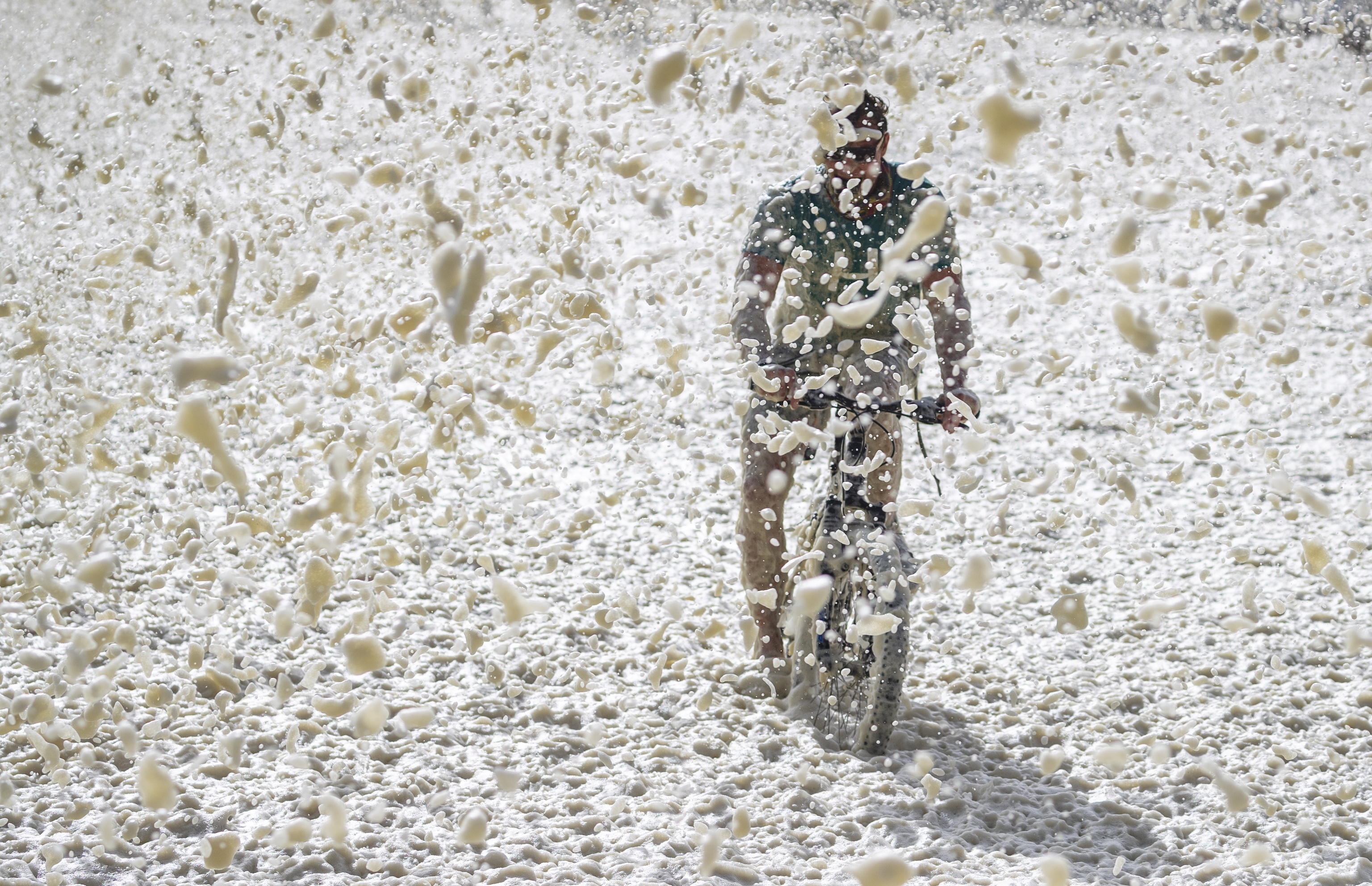 epa08543434 A man rides his bicycle through thick sea foam blowing ashore during a storm in Seapoint, Cape Town, South Africa, 13 July 2020. The third in a succession of powerful cold fronts have swept over the peninsula causing extensive damage. Waves in excess of ten meters have been crashing into the Cape's west coast with gale force winds, flooding, uprooted trees and some roofs been blown off houses being reported.  EPA/NIC BOTHMA