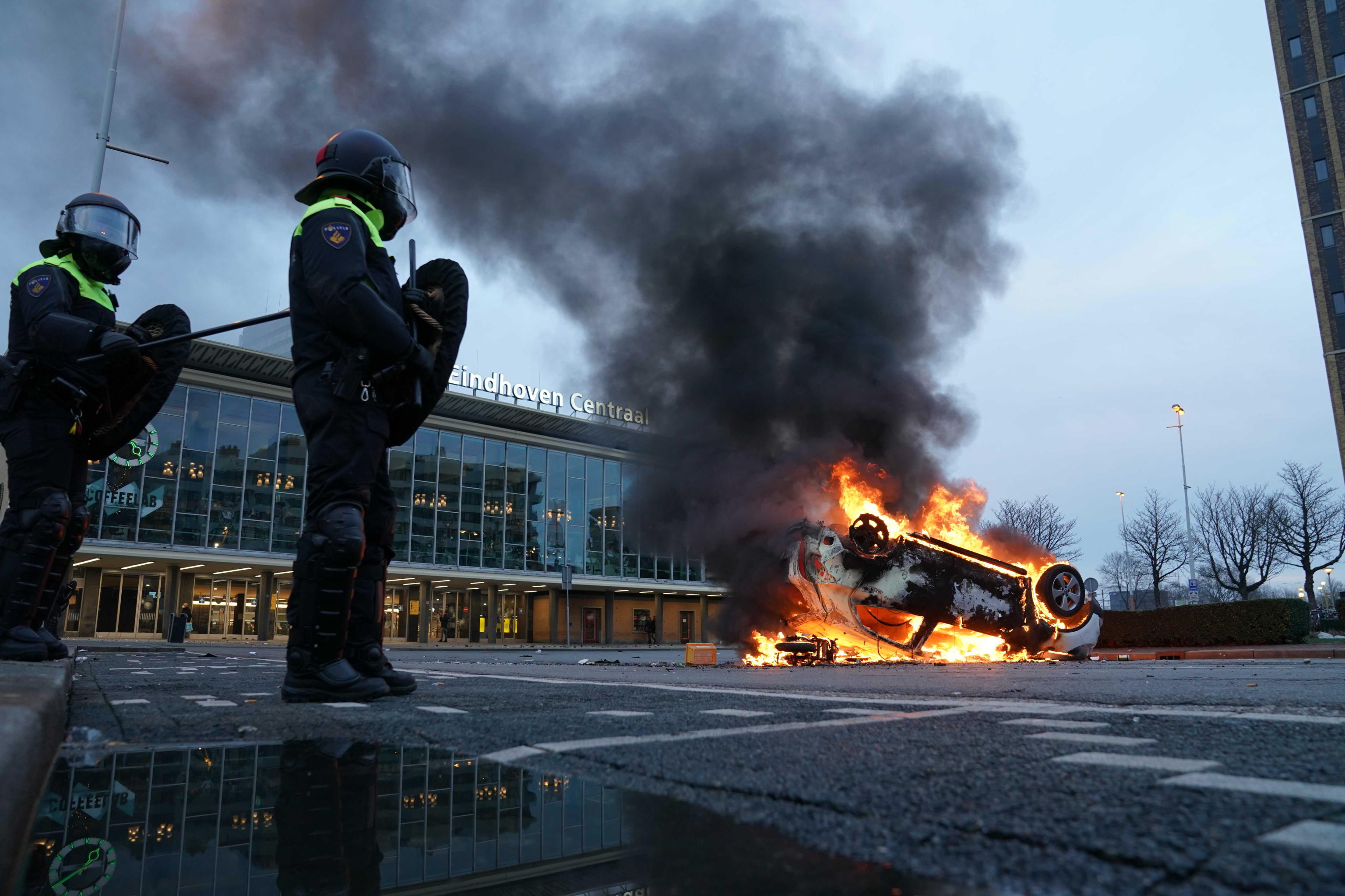 epa08963211 A car has been set on fire in front of the station on the 18 Septemberplein in Eindhoven, the Netherlands, 24 January 2021. Far-right anti-Islam movement Pegida had announced a protest which was banned by the Eindhoven Mayor Jorritsma for fear of disturbances.  EPA/ROB ENGELAAR