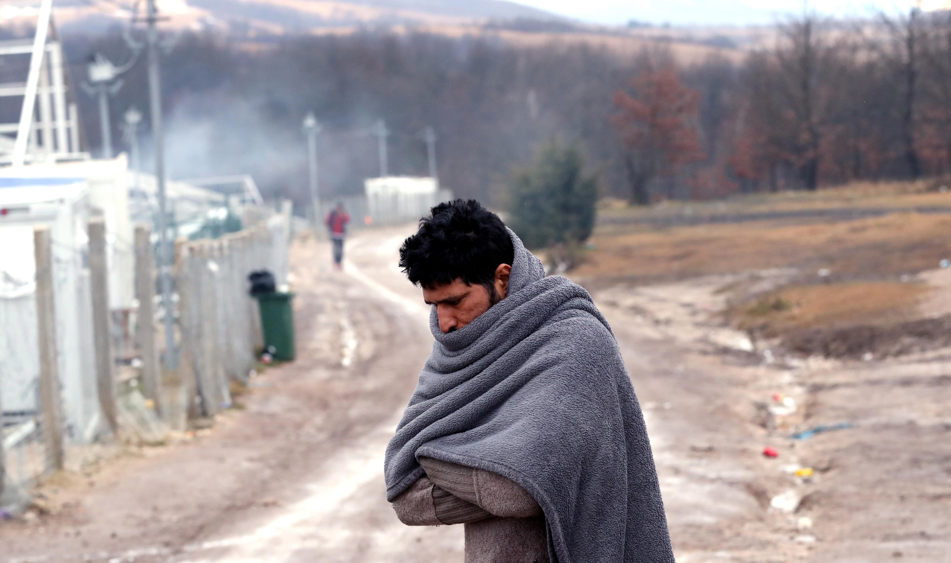 epa08914435 A migrant tries to warm himself at the Lipa camp in Bihac, Bosnia and Herzegovina, 01 January 2021. Some thousand refugees at the camp were scheduled to be relocated from the burnt-down tent camp on 31 December, yet were returned to Lipa camp. A fire on 23 December destroyed most of the camp near the city of Bihac, which has already been sharply criticized by international authorities and aid groups as unsuitable for accommodating refugees and migrants.  EPA/FEHIM DEMIR