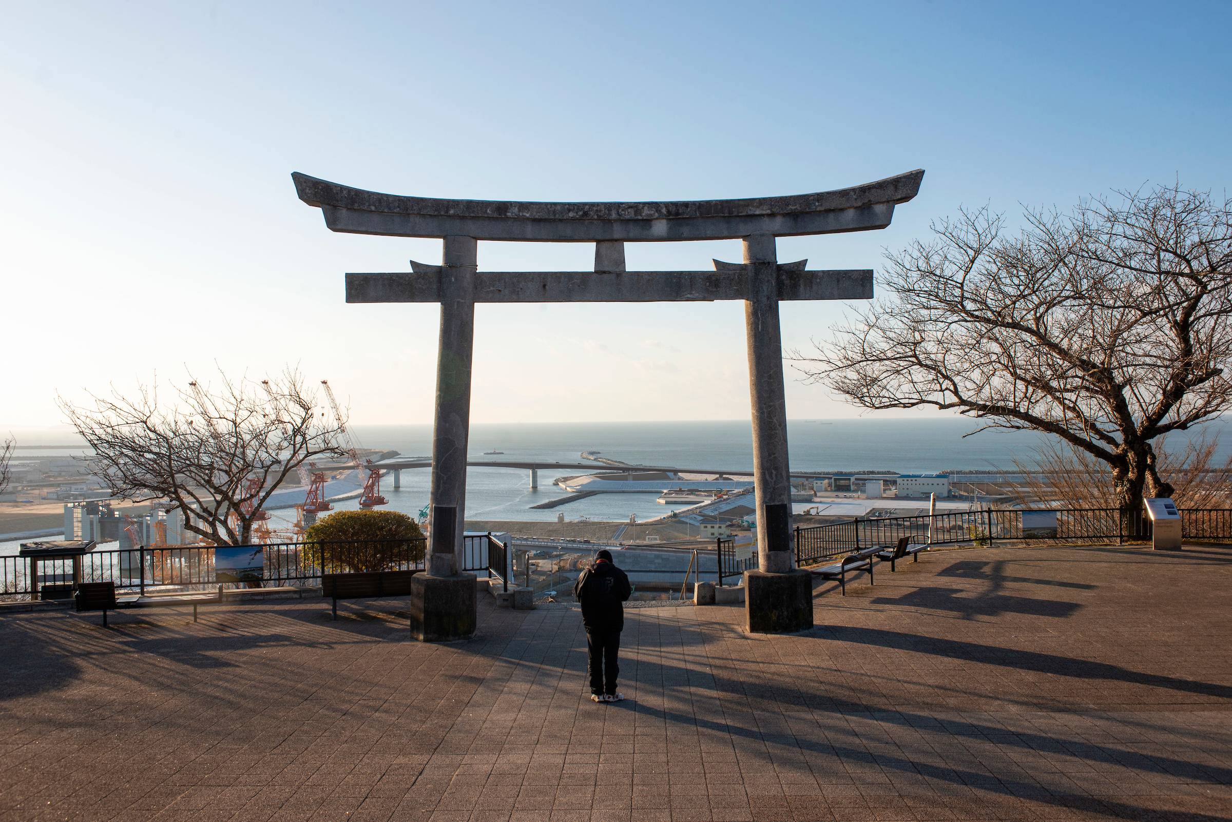 A man says an early morning prayer at the torii gate atop Mt. Hiyori, which overlooks a coastal area of Ishinomaki City, Miyagi Prefecture, Japan on 31 Jan.  2021. March 11, will mark the 10th anniversary of the quake and tsunami and wreaked havoc on the city and other parts of the Tohoku region of northeastern Japan. Photographer: Robert Gilhooly