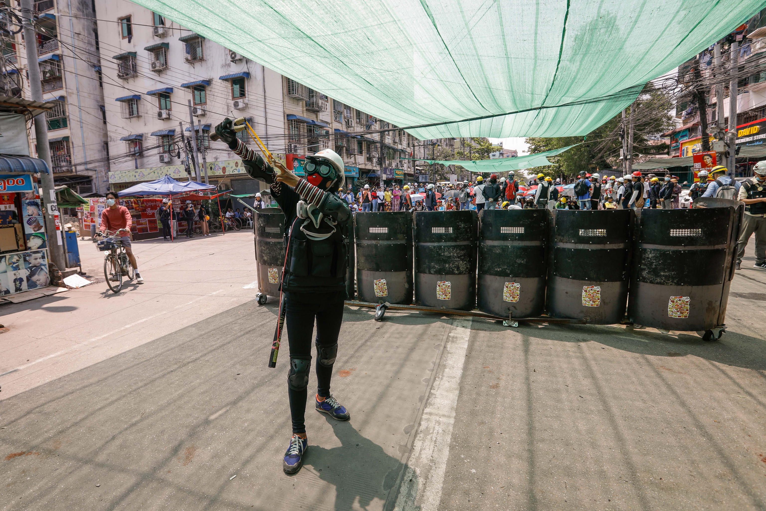 epa09081199 A female demonstrator practices a sling shot during a protest against the military coup in Yangon, Myanmar, 18 March 2021. Anti-coup protests continued despite the intensifying violent crackdowns on demonstrators by security forces.  EPA/STRINGER