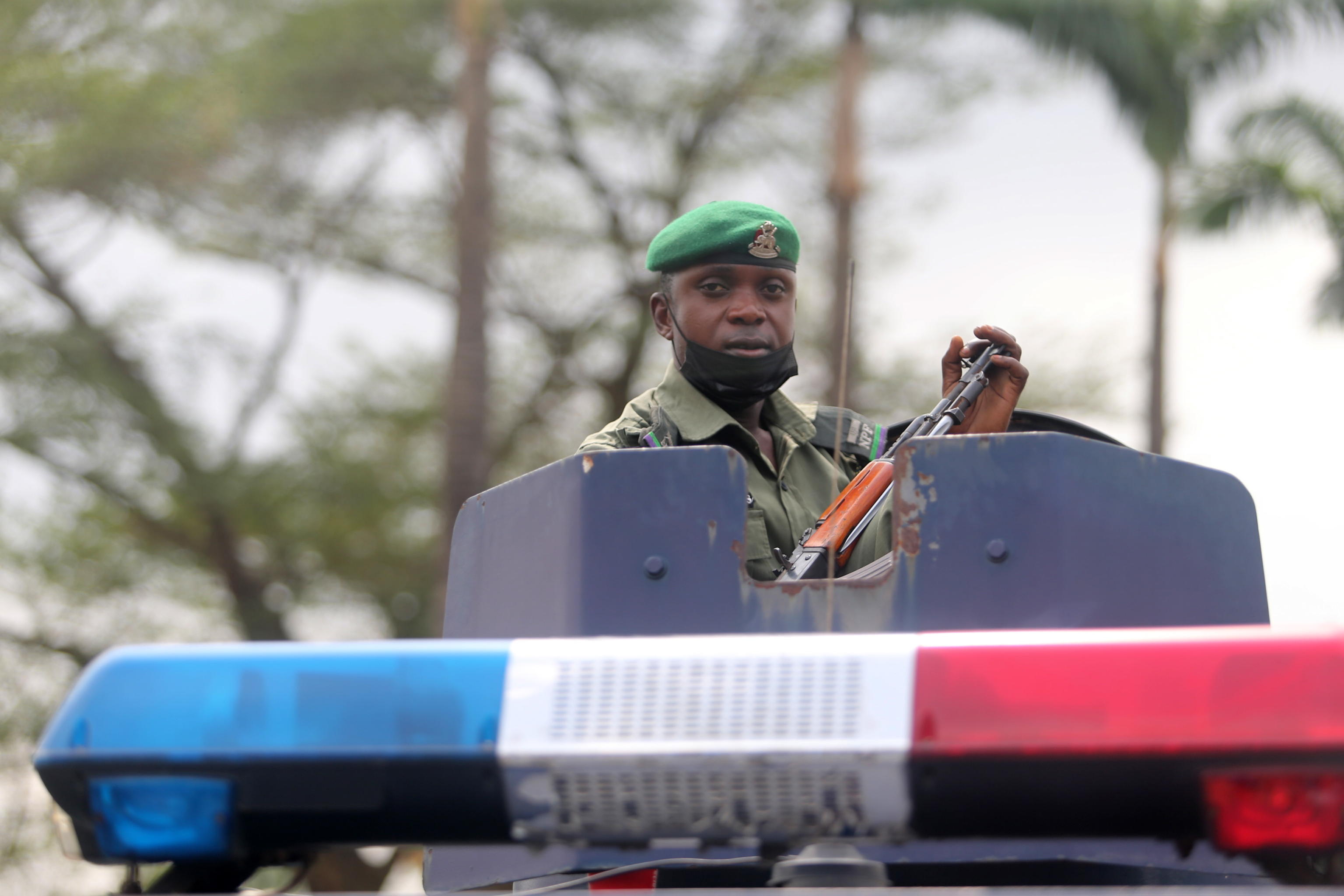 epa09065843 A policeman sits on a police amoured vehicle as he holds a gun, during a protest by the Nigeria Labour Congress (NLC) members, ahead of a planned nation-wide strike by the NLC, in Ikeja district in Lagos, Nigeria, 10 March 2021. The umbrella body of public workers in Nigeria, NLC protested on the streets of Lagos and other states in Nigeria on matters affecting their members, particularly on a planned removal of the minimum wage from the Federal government excLusive list by the Nigerian senate.  EPA/AKINTUNDE AKINLEYE