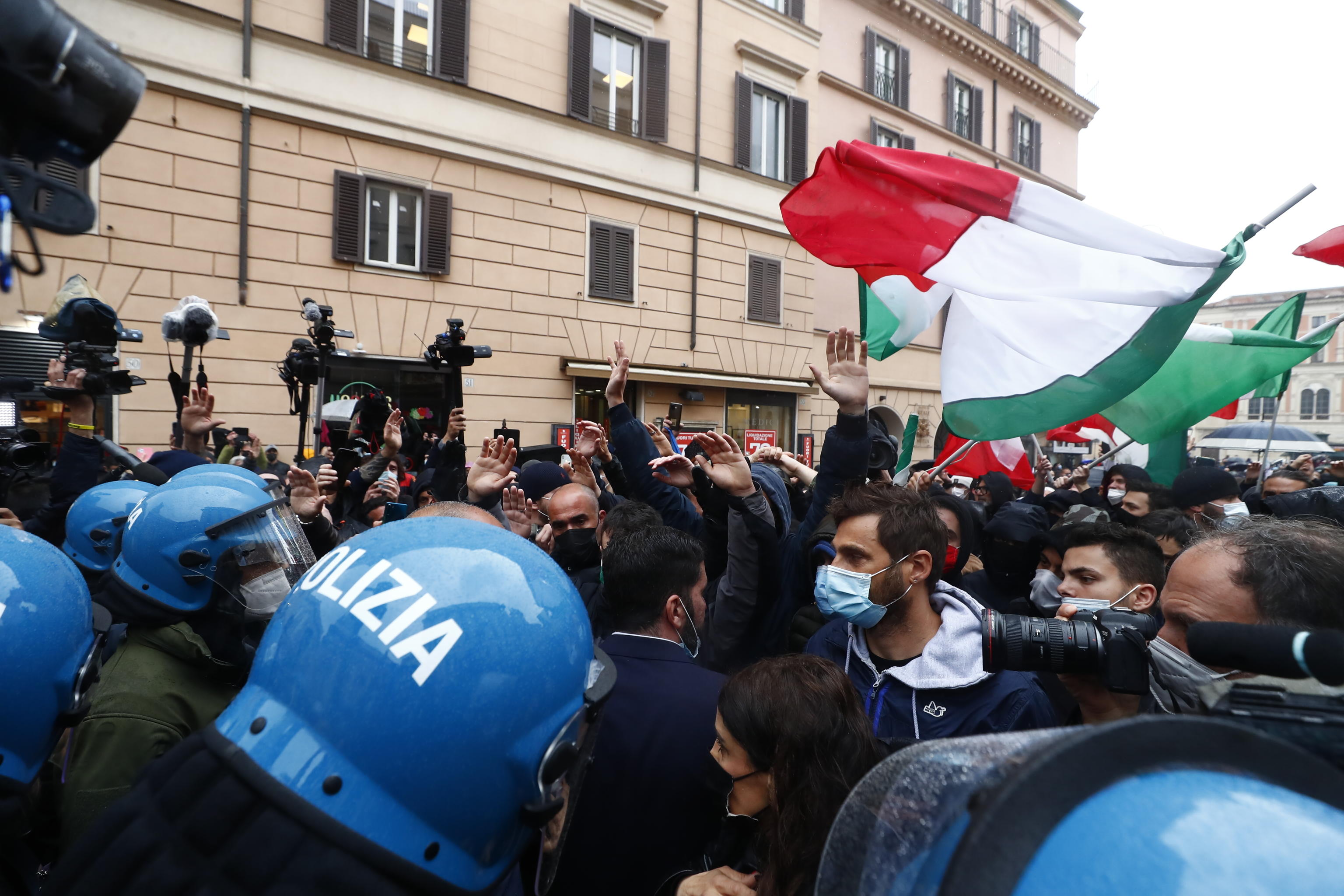 I partecipanti alla manifestazione organizzata a Piazza San Silvestro dal movmento IoApro si confrontano con le forze dell'ordine schierate in tenuta antisommossa, Roma, 12 aprile 2021. I manifestanti, alcuni con le manette, e le mani alzate chiedono di andare verso Montecitorio. ANSA/ANGELO CARCONI