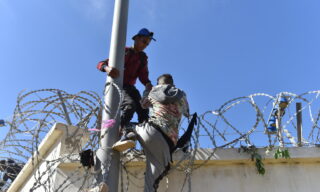 epa09210804 Migrants climb the fence in the northern town of Fnideq in an attempt to cross the border from Morocco to the Spanish enclave of Ceuta, in North Africa 18 May 2021.  In little over 24 hours a total of almost 8,000 people entered into the Spanish city of Ceuta, located in the North African coast, by sea side and hundreds of migrants continue to attempt doing so. The Spanish authorities have deployed the army to patrol on the border separating Ceuta in the Spanish side from the Moroccan side, in a bid to control this latest surge of entry attempts.  EPA/JALAL MORCHIDI