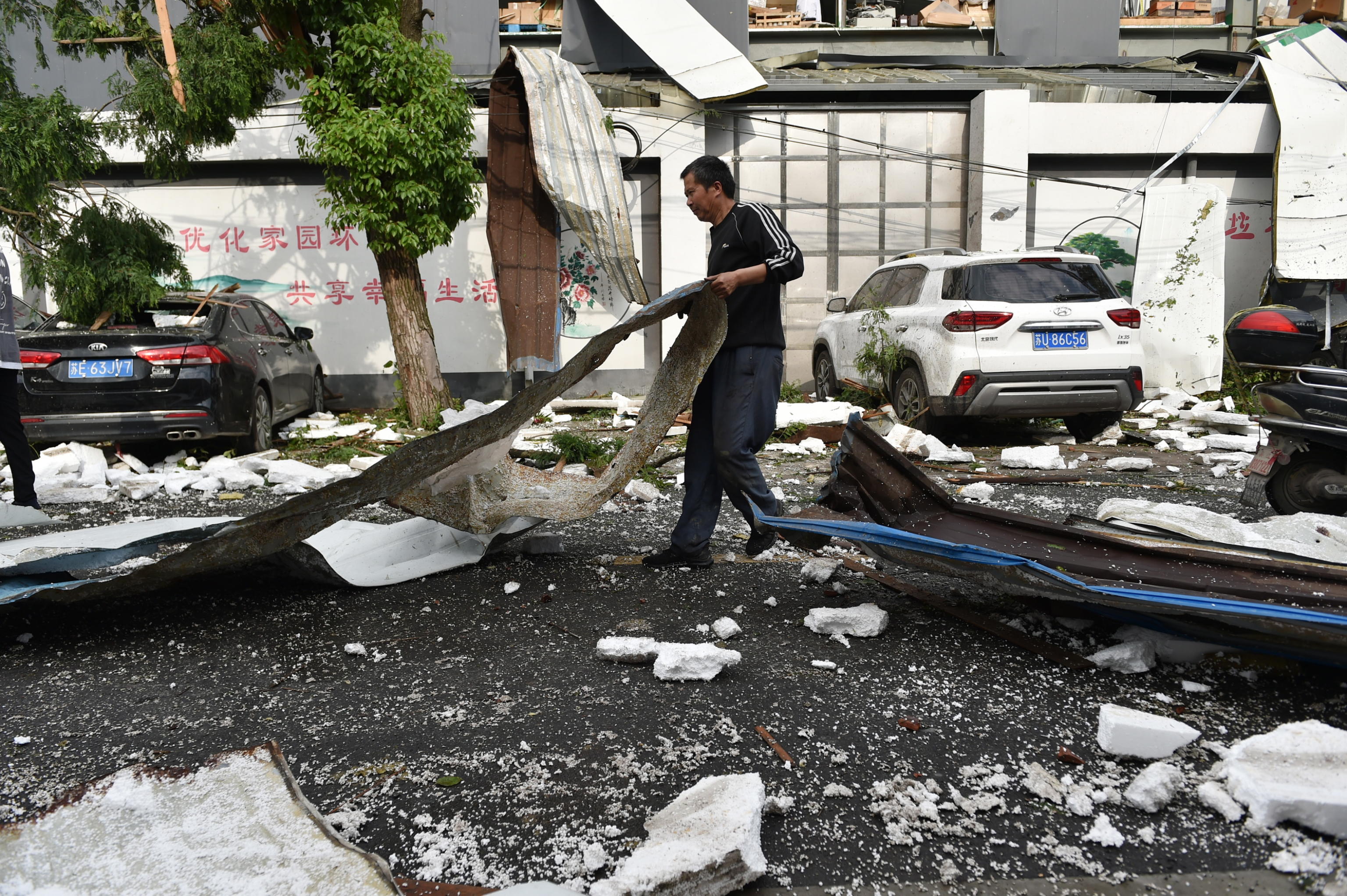 epa09200733 A villager clears the road of debris in the aftermath of a tornado in Shengze township, Suzhou, Jiangsu province, China, 15 May 2021. At least one person was killed and over 20 were injured. Another tornado hit in Wuhan, killing six people and injuring over 200.  EPA/FANG DONGXU