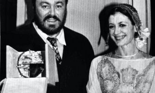 19830311-MILANO-Patrocinato da Nicola Trussardi, al termine della sfilata alla Scala, premiato il tenore Luciano Pavarotti con il premio 'Immagine Italia'. Nella foto: Luciano Pavarotti mostra il premio ricevuto al fianco di Carla Fracci. ANSA ARCHIVIO/A 11436