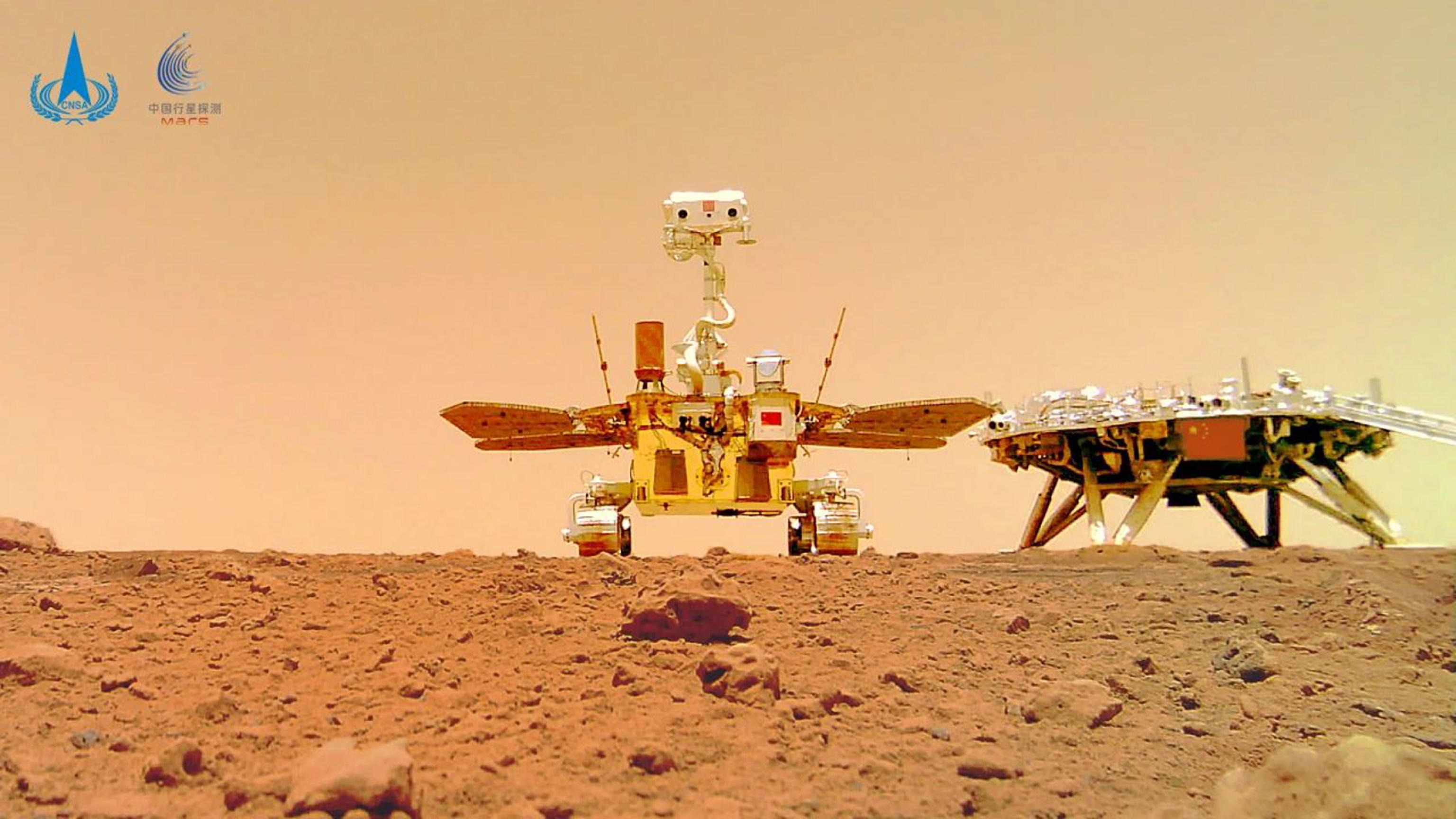 epa09261261 A handout photo made available by the China National Space Administration (CNSA) shows China's Mars rover Zhurong next to the landing platform with a Chinese national flag on it, taken by a remote camera on Mars (issued 11 June 2021). China on 11 June released new photos including rover Chinese Mars Zhurong, the landing platform, the rover together with the landing platform, and the Martian surface.  EPA/China National Space Administrat  HANDOUT EDITORIAL USE ONLY/NO SALES