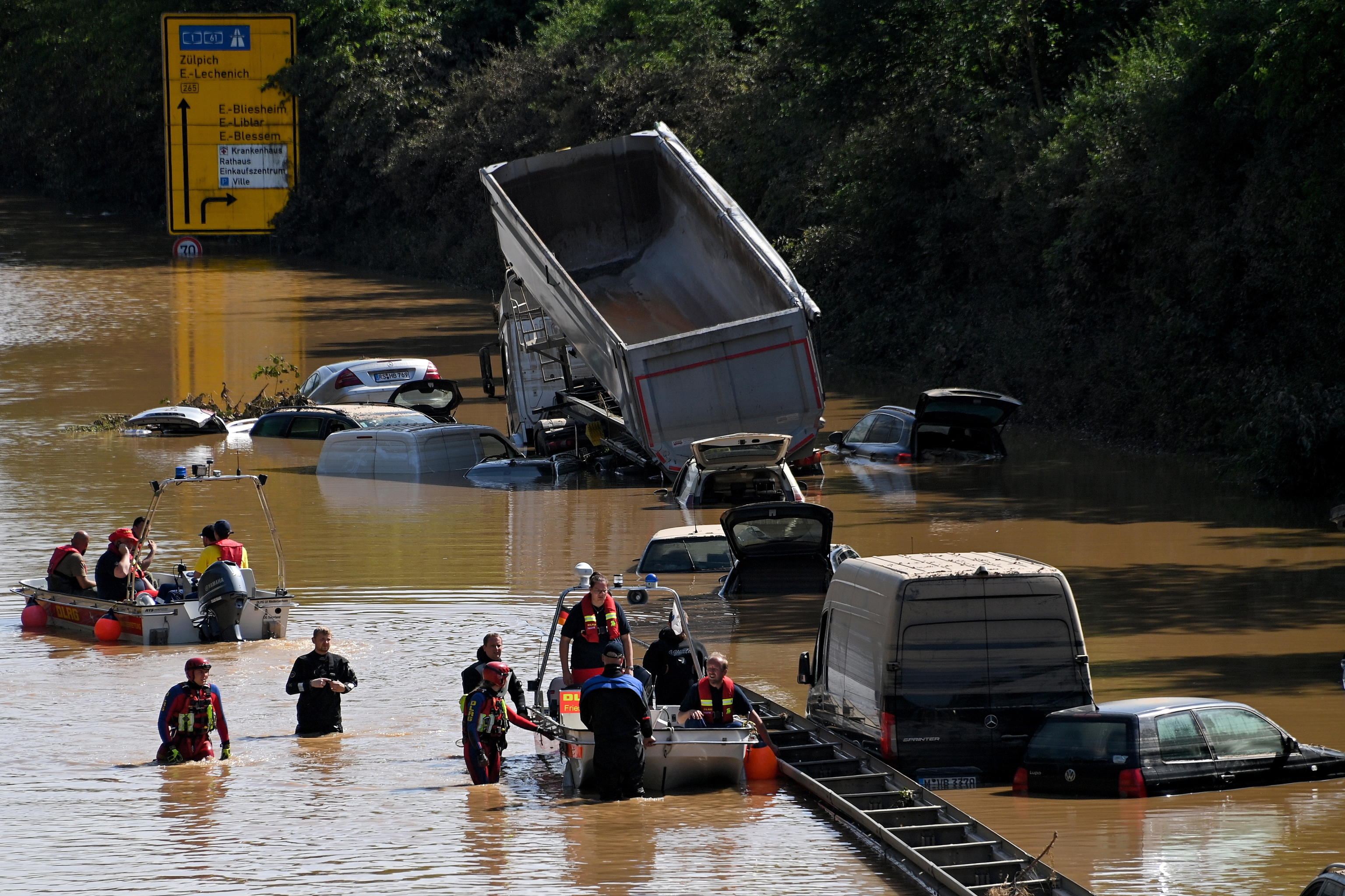epa09350667 Rescue services clear wrecked cars and trucks from the B265 federal highway in Erftstadt, Germany, 17 July 2021. Large parts arts of central Eruope were hit by heavy, continuous rain resulting in local flash floods that destroyed buildings and swept away cars. At least 140 people died in Germany.  EPA/SASCHA STEINBACH