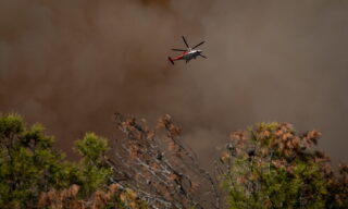 epaselect epa09203442 A helicopter flies over the Palisades Fire burning towards a hiking trail in Topanga, California, USA, 15 May 2021. The fire had burned over 700 acres by nightfall, prompting evacuations.  EPA/Christian Monterrosa