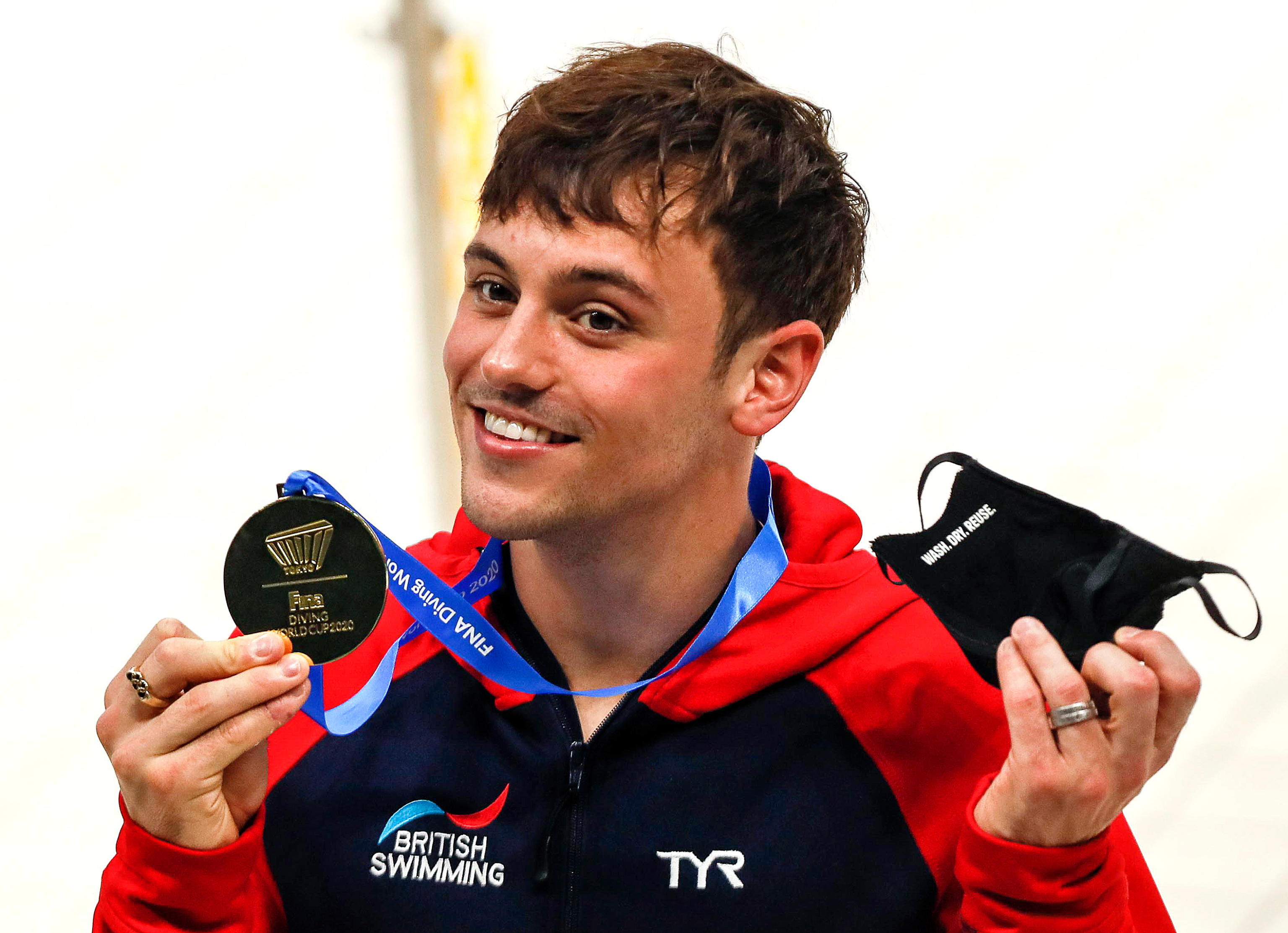 epa09177246 Tom Daley of Britain removes his protective face mask to pose with his gold medal after winning the men's 10m platform final of the FINA Diving World Cup 2021 at Tokyo Aquatics Center in Tokyo, Japan, 04 May 2021.  EPA/KIMIMASA MAYAMA