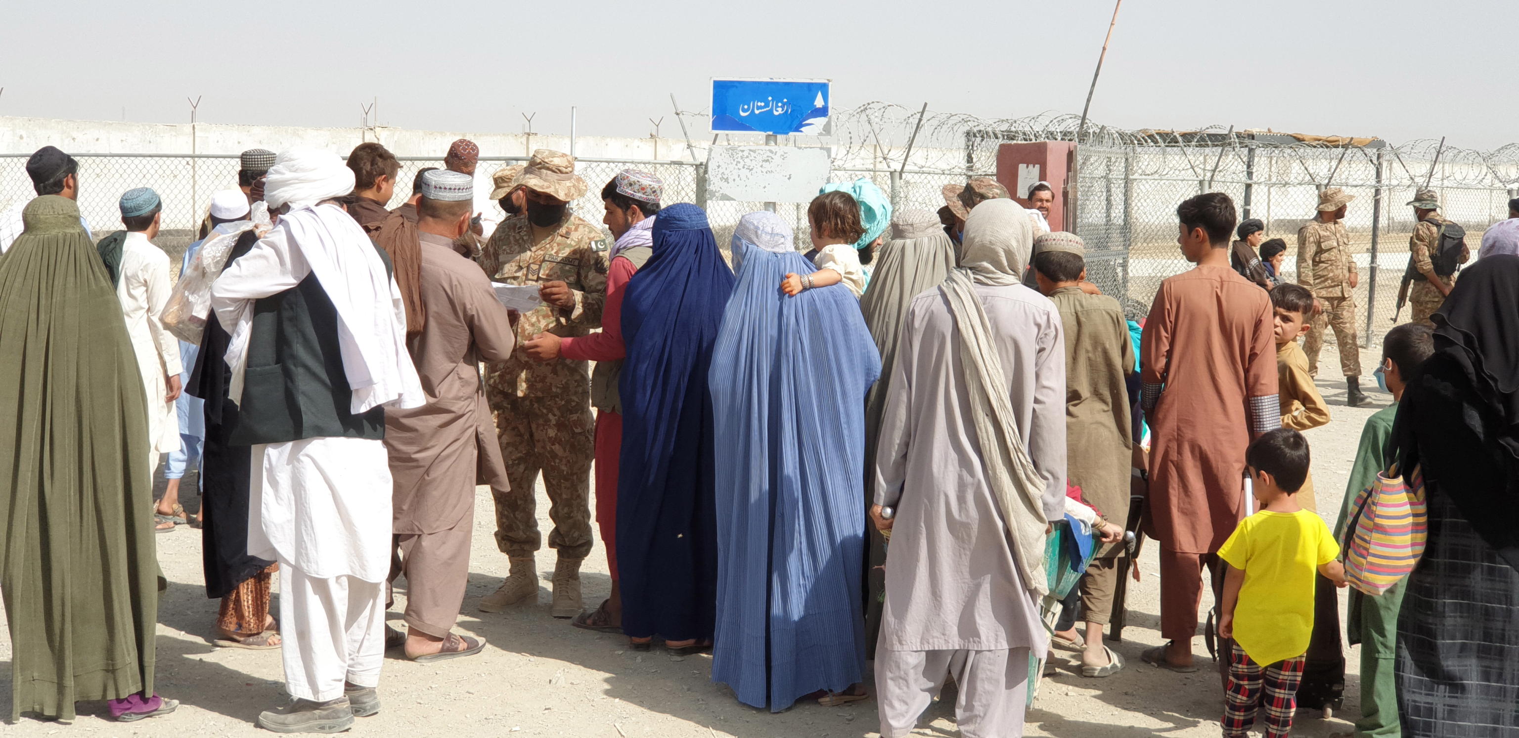 epa09431841 People cross into Afghanistan at Chaman border point, in Pakistan, 27 August 2021. Two explosions on 26 August outside Kabul's international airport left more than 60 Afghan civilians dead and 140 others wounded, while the United States military said that 12 of its personnel died.  EPA/STRINGER