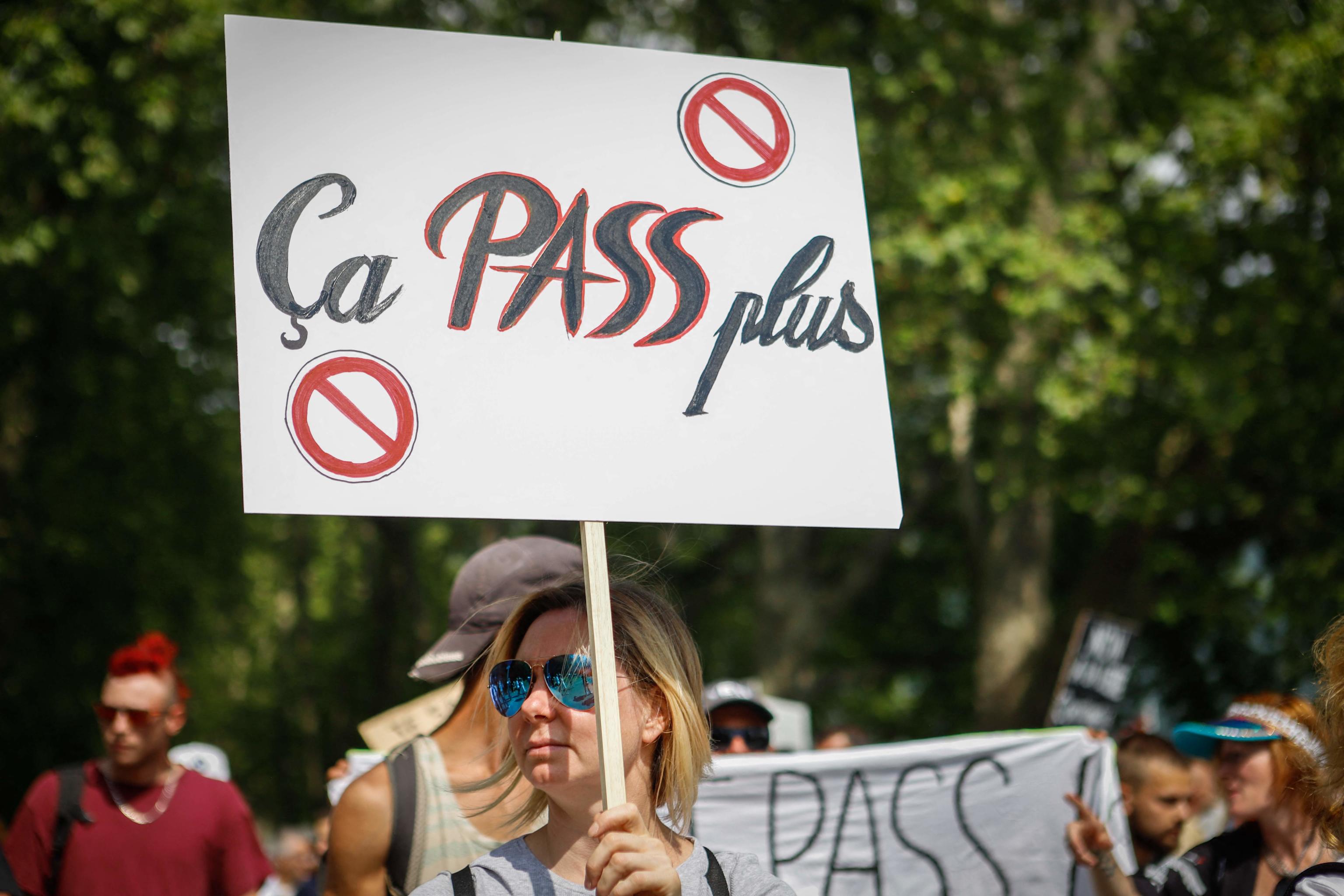 A protestor holds a placard reading "it won't pass anymore" during a demonstration against the compulsory vaccination for certain workers and the mandatory use of the health pass called by the French government in Annecy, eastern France, on July 24, 2021. - Since July 21, people wanting to go to in most public spaces in France have to show a proof of Covid-19 vaccination or a negative test, as the country braces for a feared spike in cases from the highly transmissible Covid-19 Delta variant. (Photo by Sophie RODRIGUEZ / AFP)