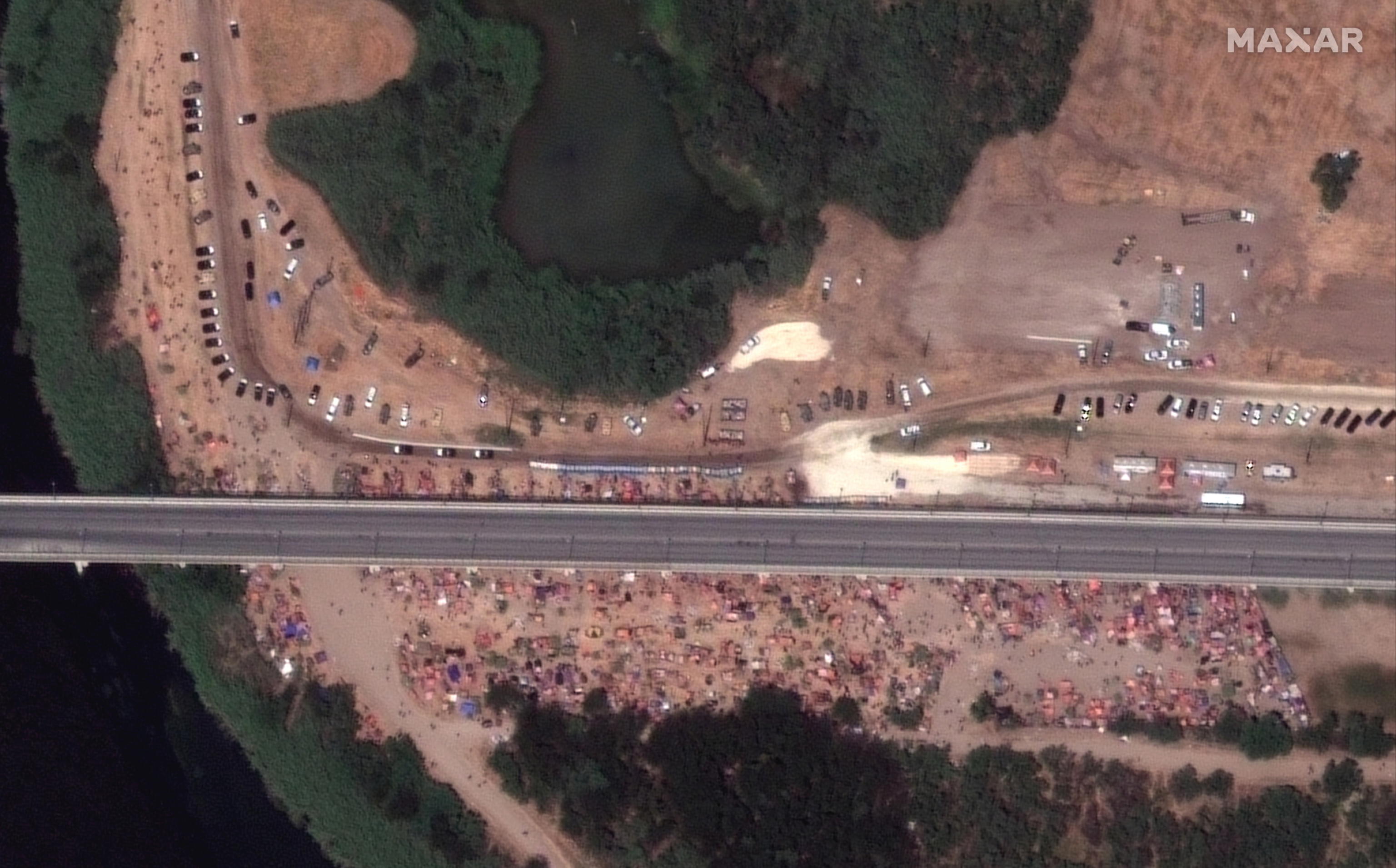 epa09478319 A handout satellite image made available by Maxar Technologies shows hundreds of migrants next to International Bridge on the Mexico-US border near Del Rio, Texas, USA, 18 September 2021 (issued 20 September 2021). More than 14,000 people have crossed the Rio Grande river from Mexico creating a humanitarian crisis. The Biden administration has started to fly the migrants back to Haiti according to federal officials.  EPA/MAXAR TECHNOLOGIES HANDOUT HANDOUT -- MANDATORY CREDIT: SATELLITE IMAGE 2021 MAXAR TECHNOLOGIES -- the watermark may not be removed/cropped -- HANDOUT EDITORIAL USE ONLY/NO SALES