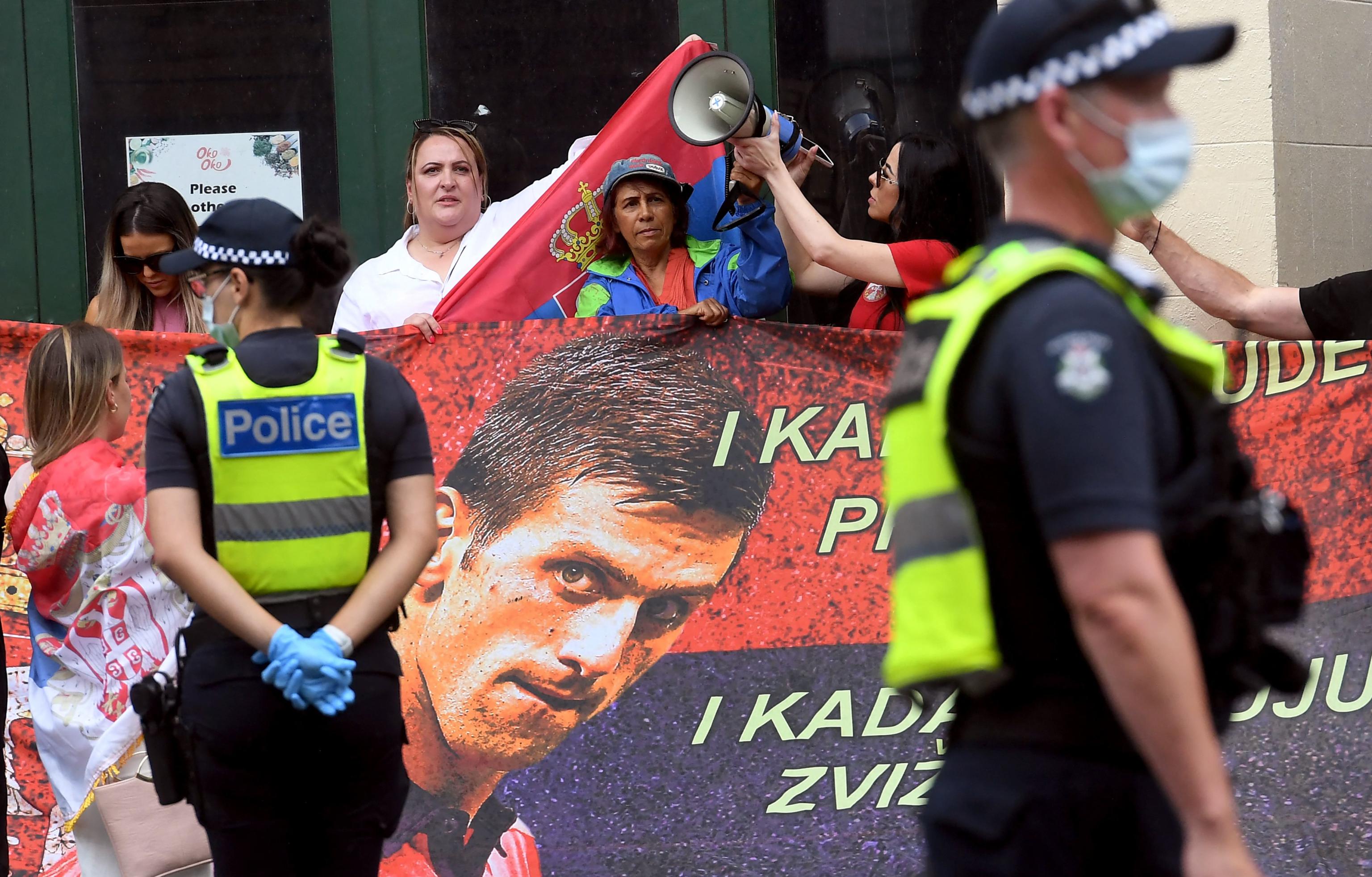 People hold placards up at a government detention centre where Serbia's tennis champion Novak Djokovic is reported to be staying in Melbourne on January 7, 2022, after Australia said it had cancelled the entry visa of Djokovic, opening the way to his detention and deportation in a dramatic reversal for the tennis world number one. (Photo by William WEST / AFP)