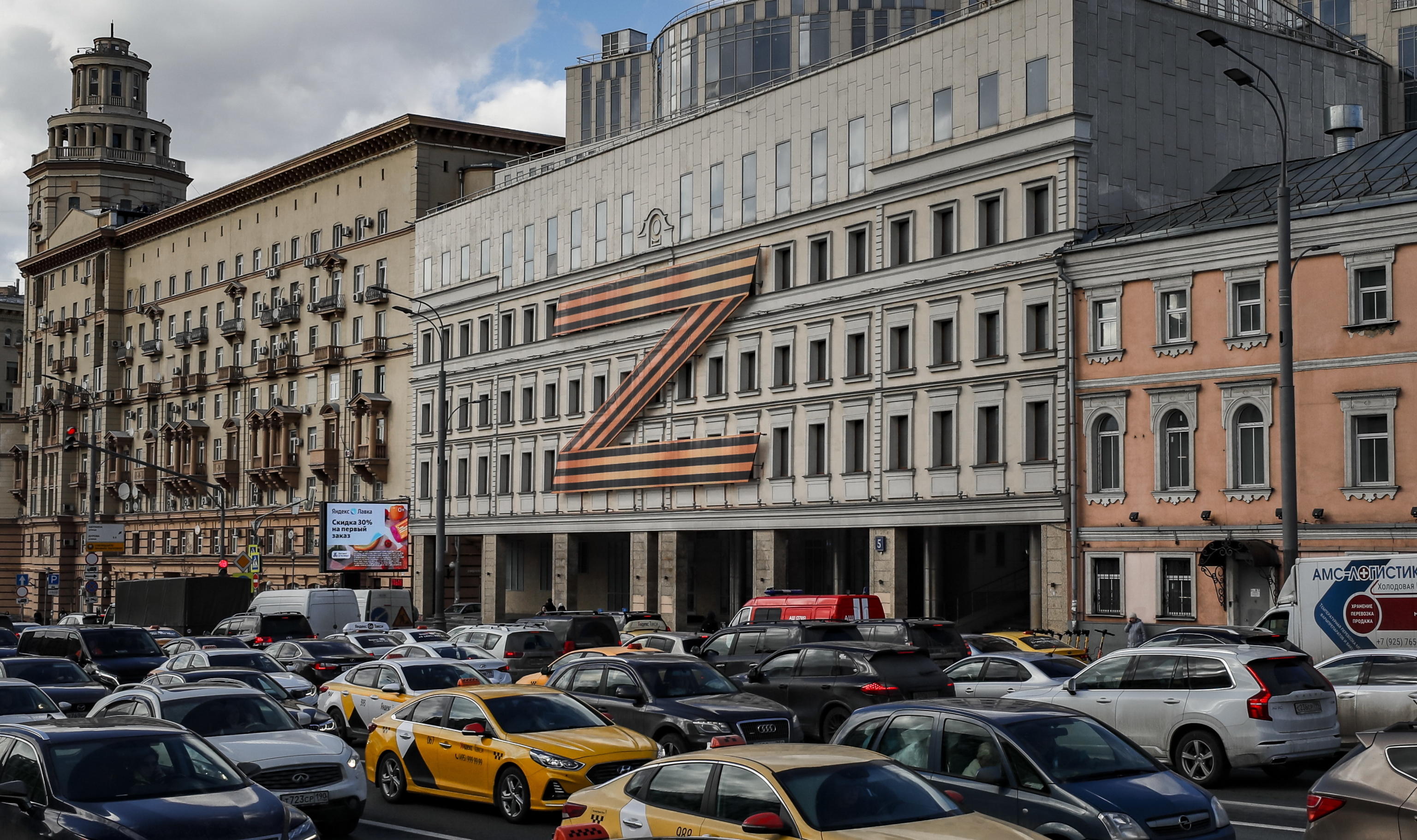 epa09860440 Cars stuck in traffic in front of a theatre building decorated with the letter Z in Moscow, Russia, 30 March 2022. The letter Z has been used by Russian forces as an identifying sign on their vehicles in Ukraine. On 24 February Russian troops had entered Ukrainian territory in what the Russian president declared a 'special military operation', resulting in fighting and destruction in the country, a huge flow of refugees, and multiple sanctions against Russia.  EPA/YURI KOCHETKOV