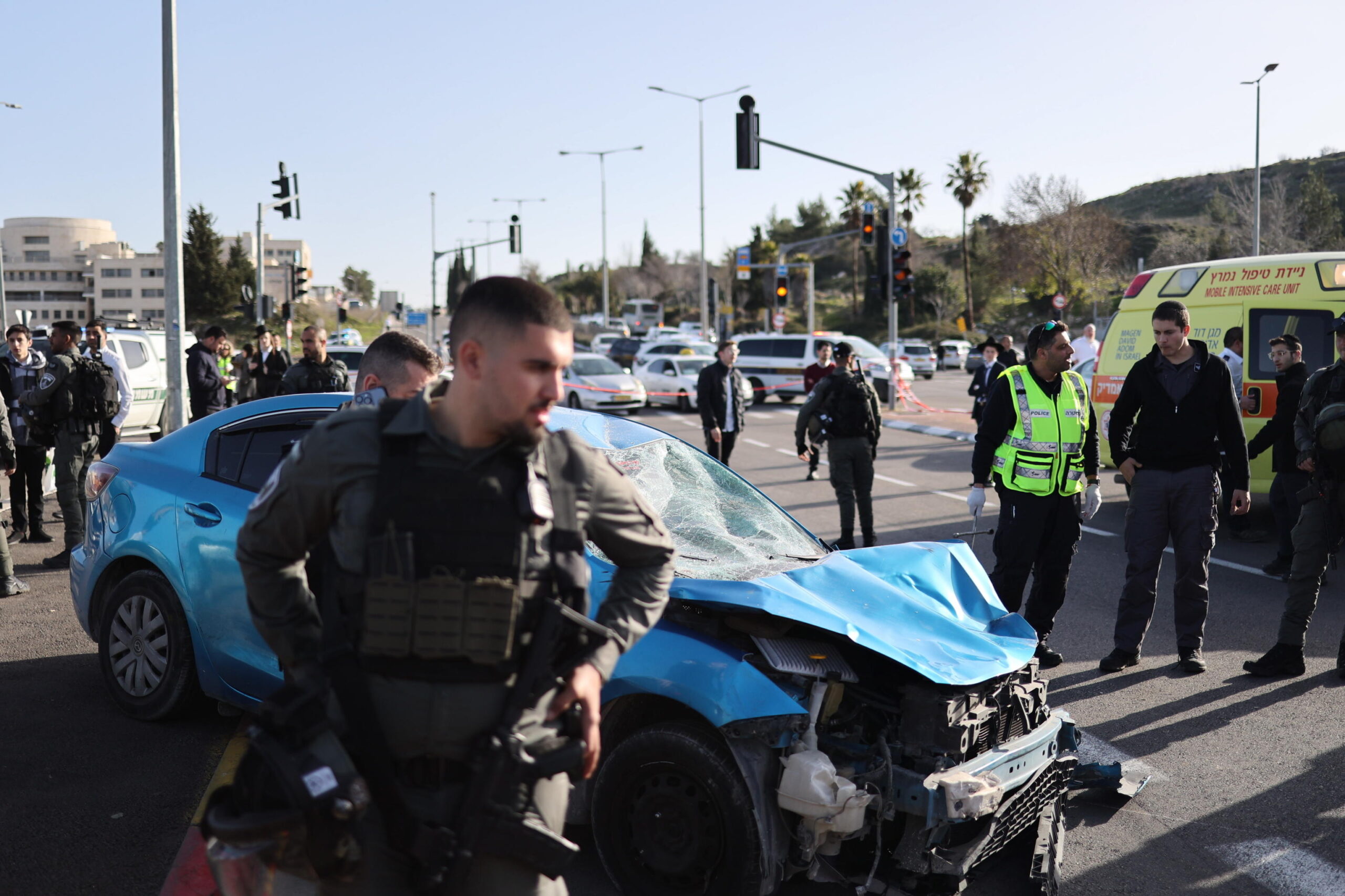 epa10459092 Israeli security forces and rescuers work at the site of a car ramming attack in Jerusalem, Israel 10 February 2023. A car driver was ramming people who were waiting at a bus stop in Ramrot, east of Jerusalem, police said. Multiple people were injured, including children, police added.  EPA/STR