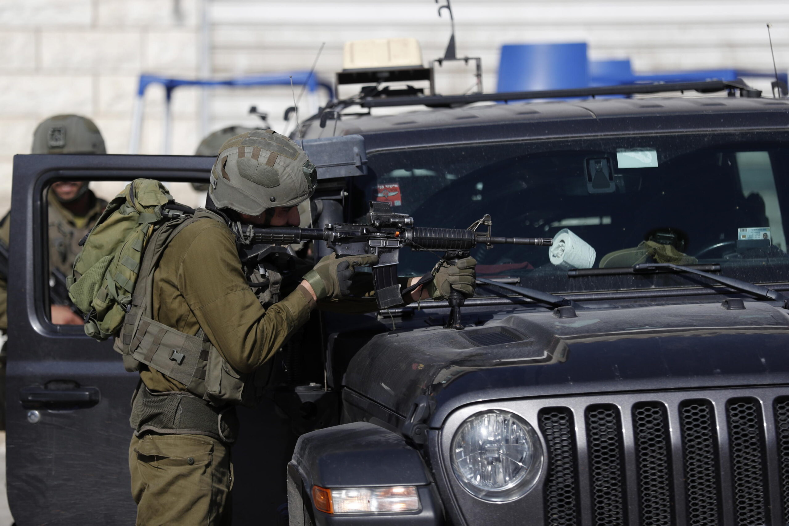 epa10493604 Israeli troops stand guard in the West Bank town of Hawera after a day of violence and tension, near the West Bank city of Nablus, 27 February 2023. According to Israeli authorities on 26 February, an attacker opened fire toward an Israeli vehicle driving through the town of Hawera, killing two Israelis who were onboard. Later the same day, dozens of Israeli settlers attacked the town and nearby villages setting Palestinian owned vehicles and homes on fire. One Palestinian was killed and dozens more were wounded. Israeli President Isaac Herzog on 26 February condemned the riots and the attacks against innocents and urged the settlers to stop.  EPA/ATEF SAFADI