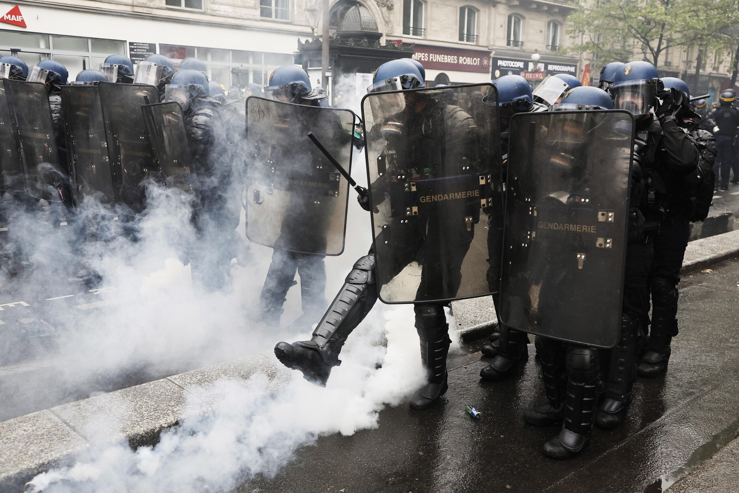 epa10602087 A riot police kicks a tear gas canister during clashes at the annual May Day march in Paris, France, 01 May 2023. Despite the Constitutional Council's adoption of the law on 14 April raising the retirement age in France from 62 to 64 years old, protests against pension reform are being held in France on this International Workers' Day. Following the filing of a new appeal by the left-wing senators, a new decision is expected on 03 May.  EPA/CHRISTOPHE PETIT TESSON