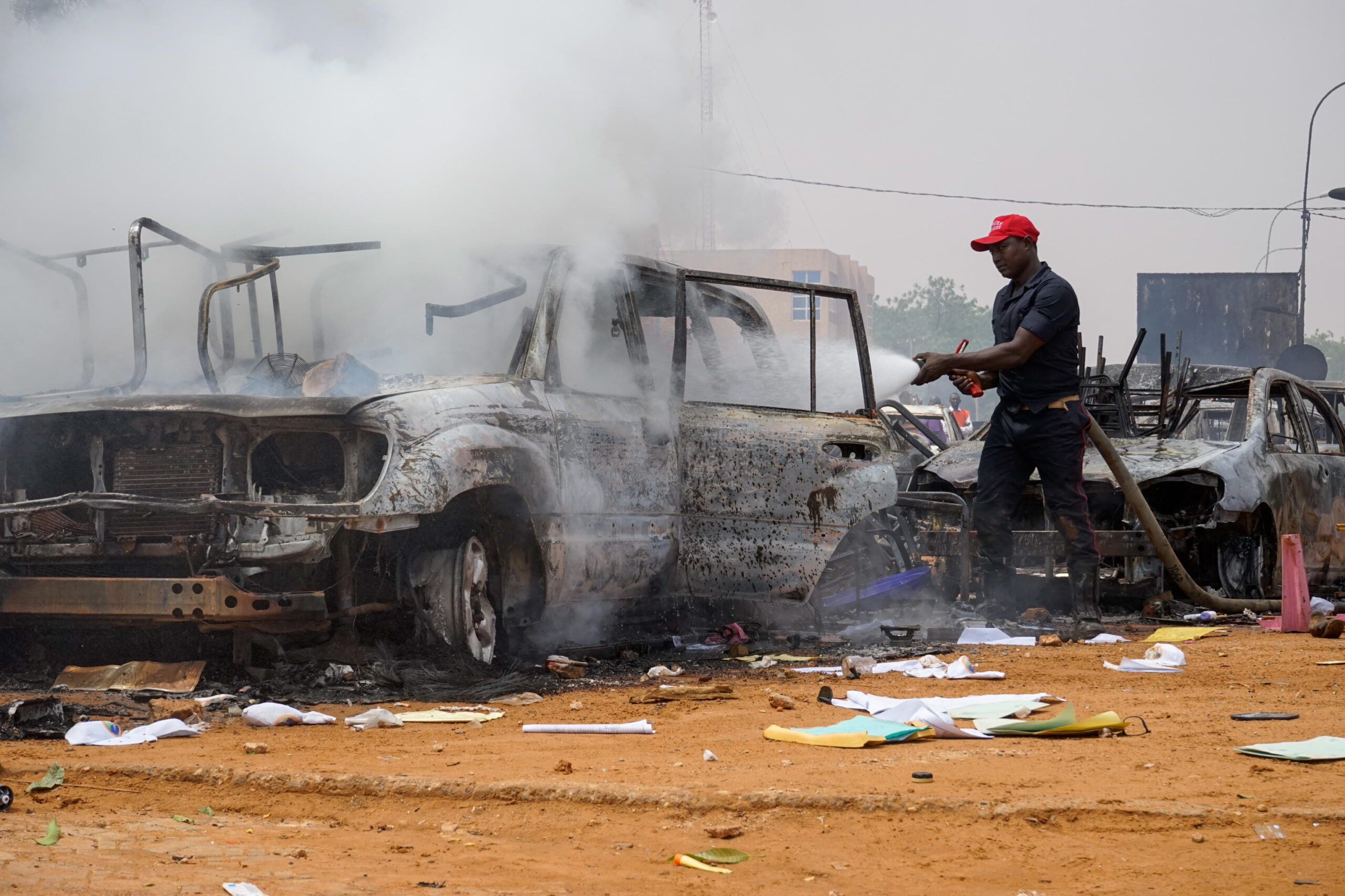 A firefighter hoses torched cars near the Nigerien Party for Democracy and Socialism headquarters in Niamey, Niger, 27 July 2023. ANSA/STR