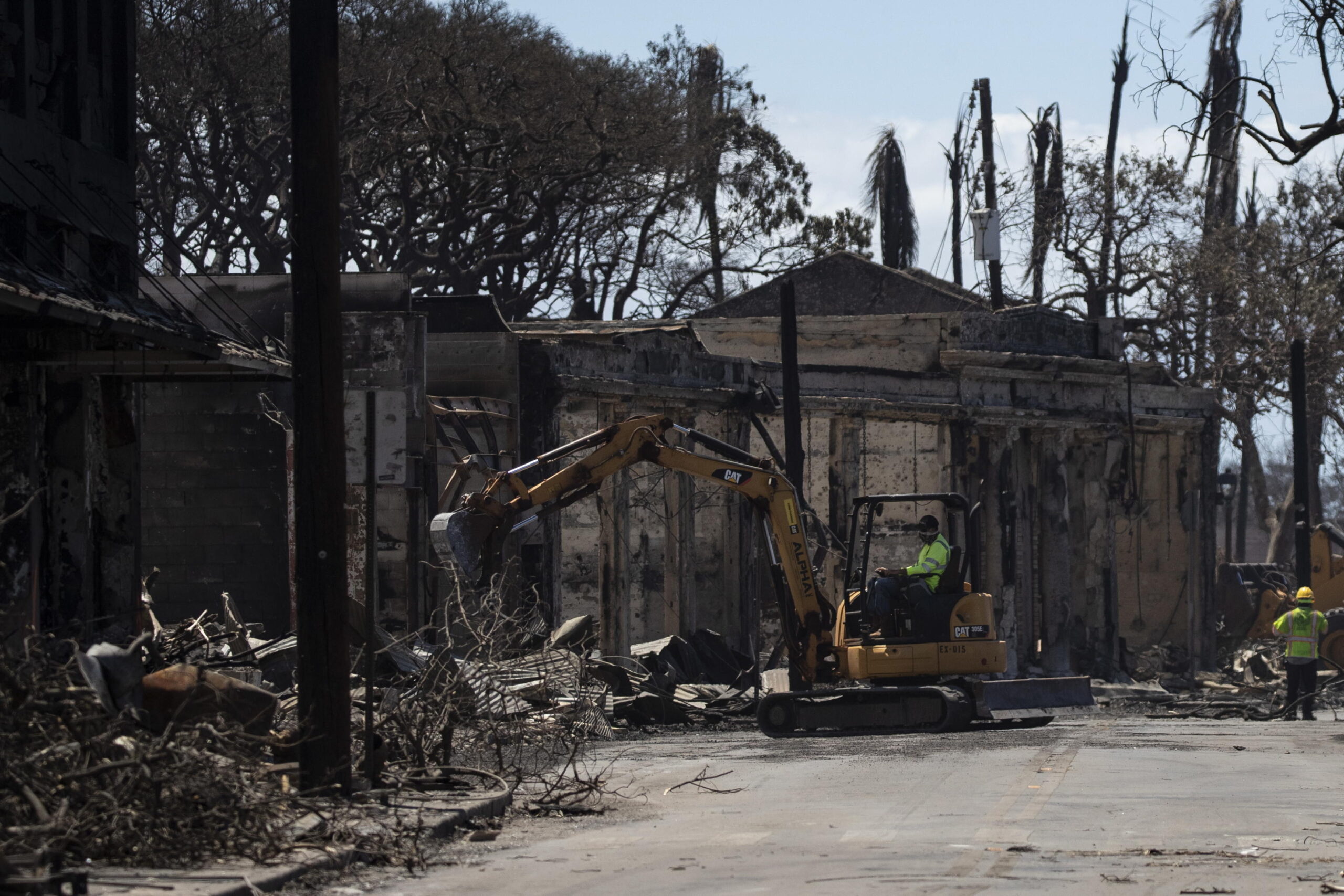 epa10796012 Workers clean the streets after a wild fire swept through the city of Lahaina only leaving ruins, Hawaii, USA, 11 August 2023. At least 67 people were killed in the wildfires burning in Maui, which is considered the largest natural disaster in Hawaii's state history.  EPA/ETIENNE LAURENT