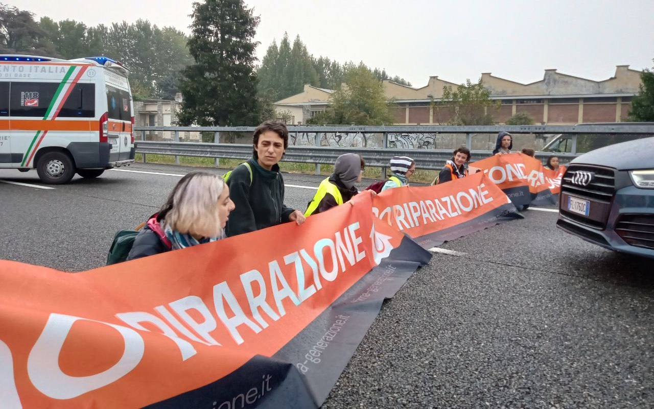 «Ho deciso di incollarmi alla strada per difendere la vita umana». Il blitz di Ultima Generazione blocca la Milano-Torino per 2 ore – Il video