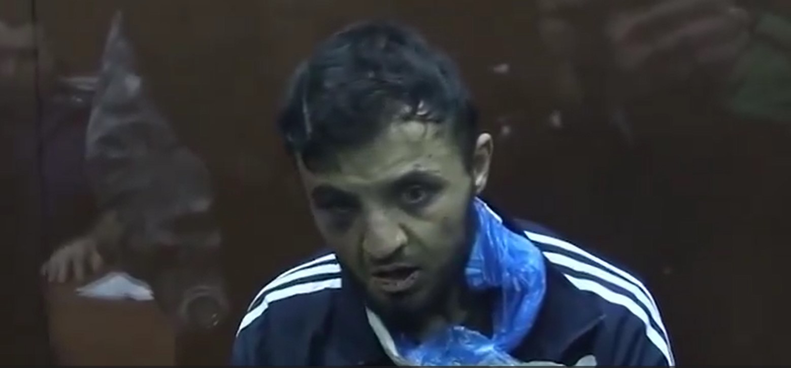 Occhio nero, sguardo nel vuoto. Uno dei terroristi della strage di Mosca davanti alla Corte – Il video