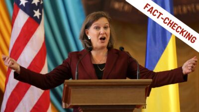 Victoria Nuland parla da un podio istituzionale con le bandiere di Stati Uniti e Ucraina sullo sfondo; l'immagine include un bollino grafico nell'angolo in alto a destra con la scritta "FACT-CHECKING".