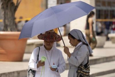 Due religiosi si riparano sotto un ombrello per il caldo record