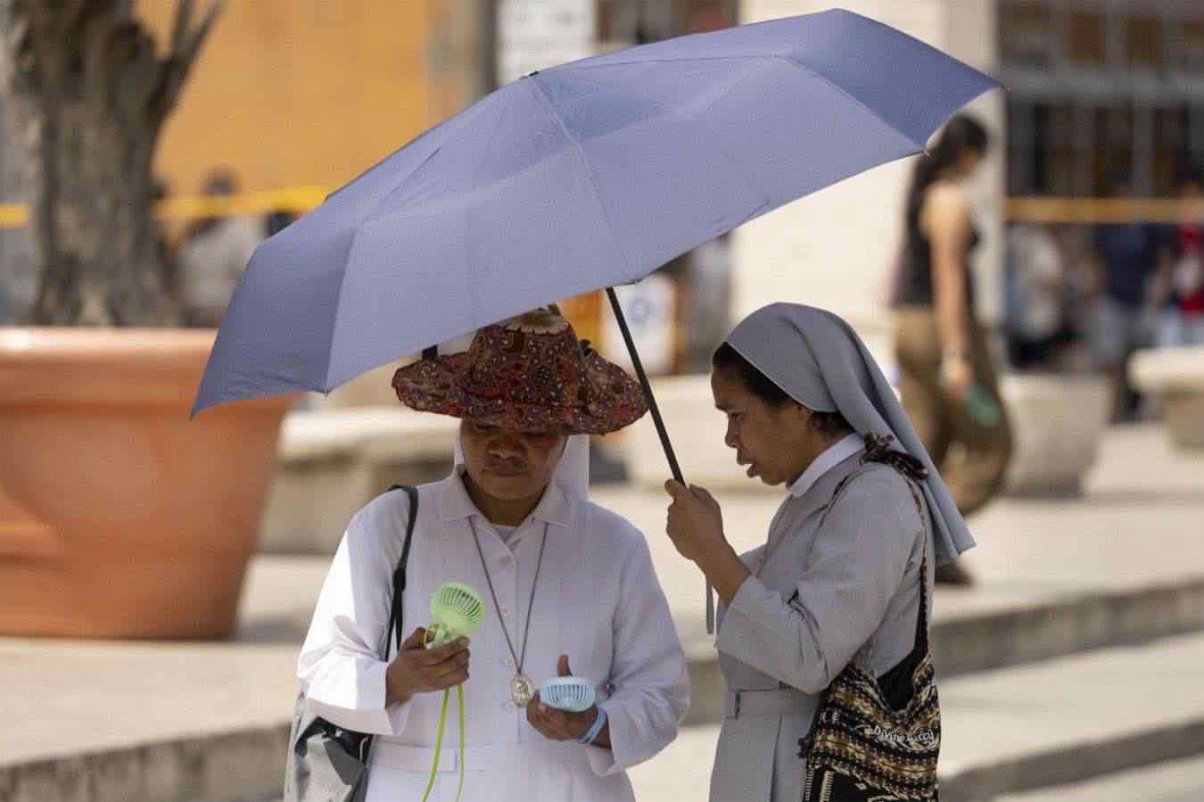 Due religiosi si riparano sotto un ombrello per il caldo record