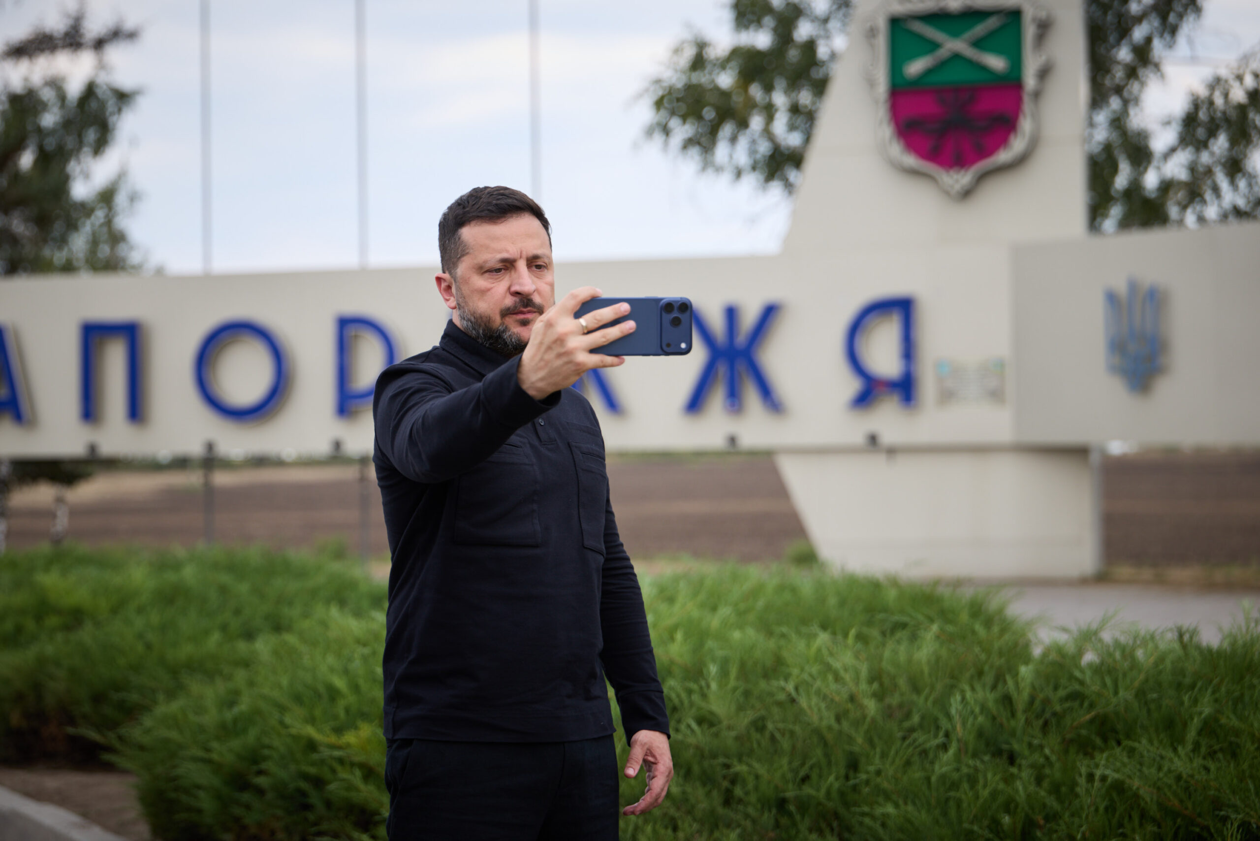 Volodymyr Zelensky si riprende con lo smartphone davanti al cartello di ingresso a Zaporizhzhia