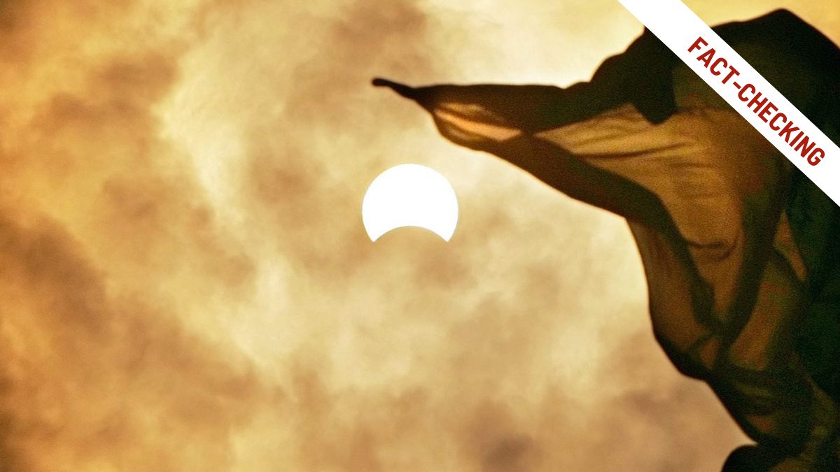 Eclissi solare parziale fotografata con una bandiera in primo piano su un cielo nuvoloso dai toni caldi