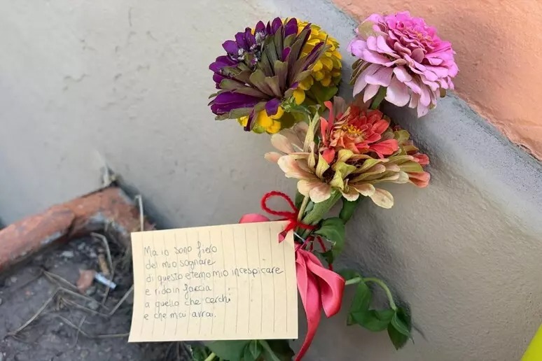 In via Paolo Fabbri a Bologna, le canzoni di Guccini risuonano a tutto volume mentre i cittadini lasciano mazzi di fiori e biglietti
