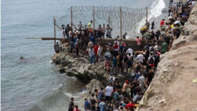 Migranti ammassati sugli scogli del Tarajal al confine tra Marocco e Ceuta durante l'attraversamento del 31 luglio 2026